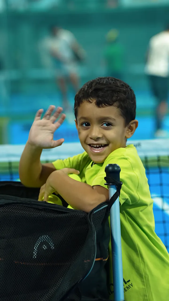 A smiling young player waving from the court